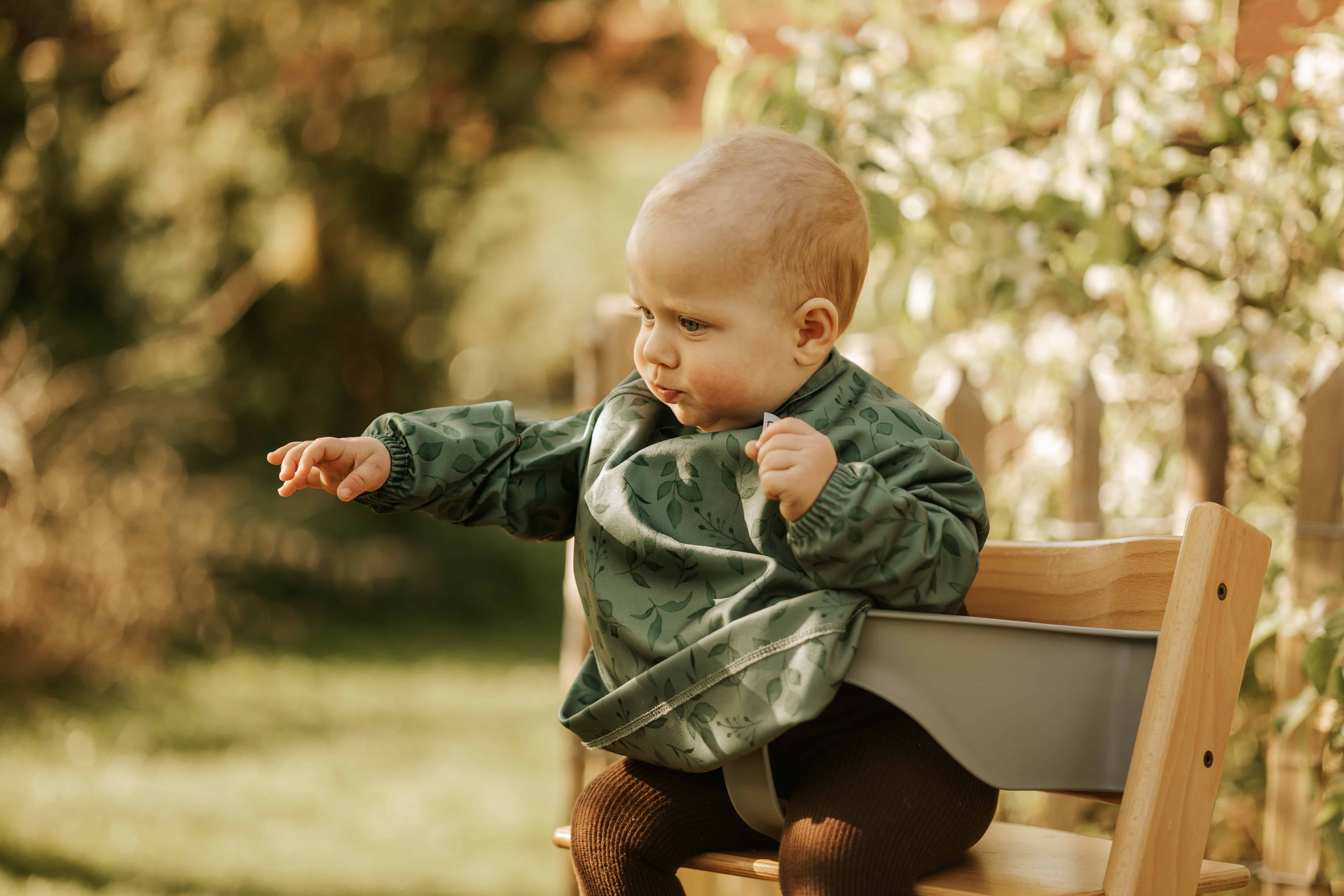 Baby med en langærmet hagesmæk med lomme